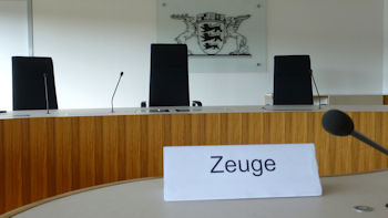 Blick auf die Richterbank im Landesarbeitsgericht Baden-Württemberg und im Hintergrund das Landeswappen.
